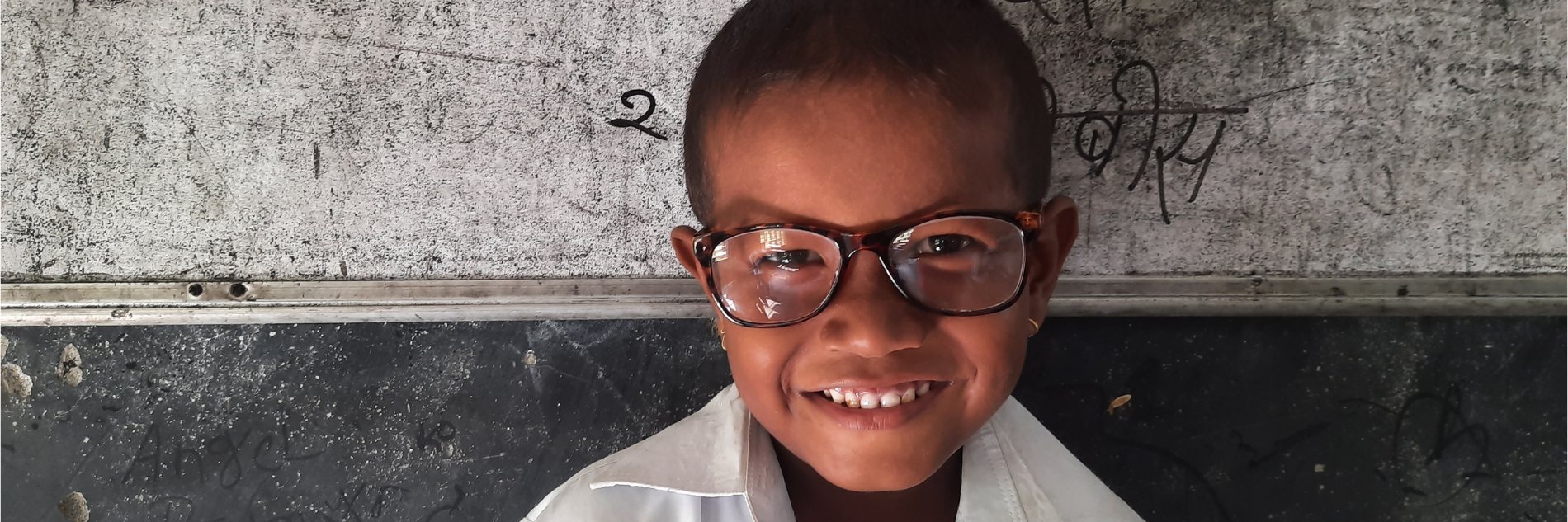 Afrikaans jongetje voor schoolbord met bril op