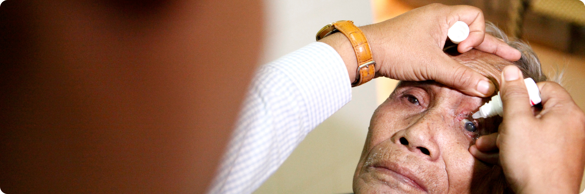 Oude man krijgt oogdruppels tijdens zijn oogbehandeling, Cambodja