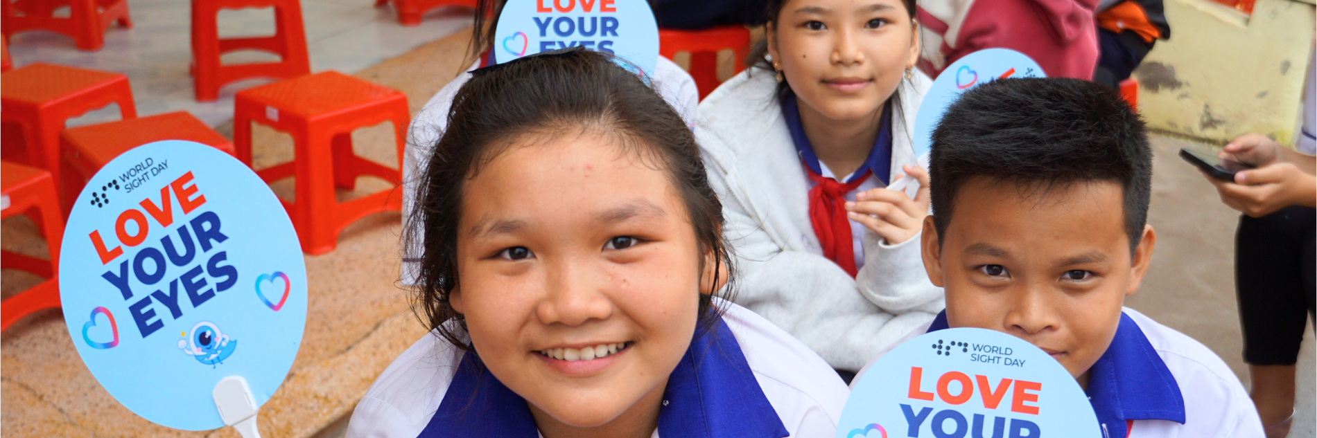 Drie kinderen met bordjes van World Sight Day in hun hand