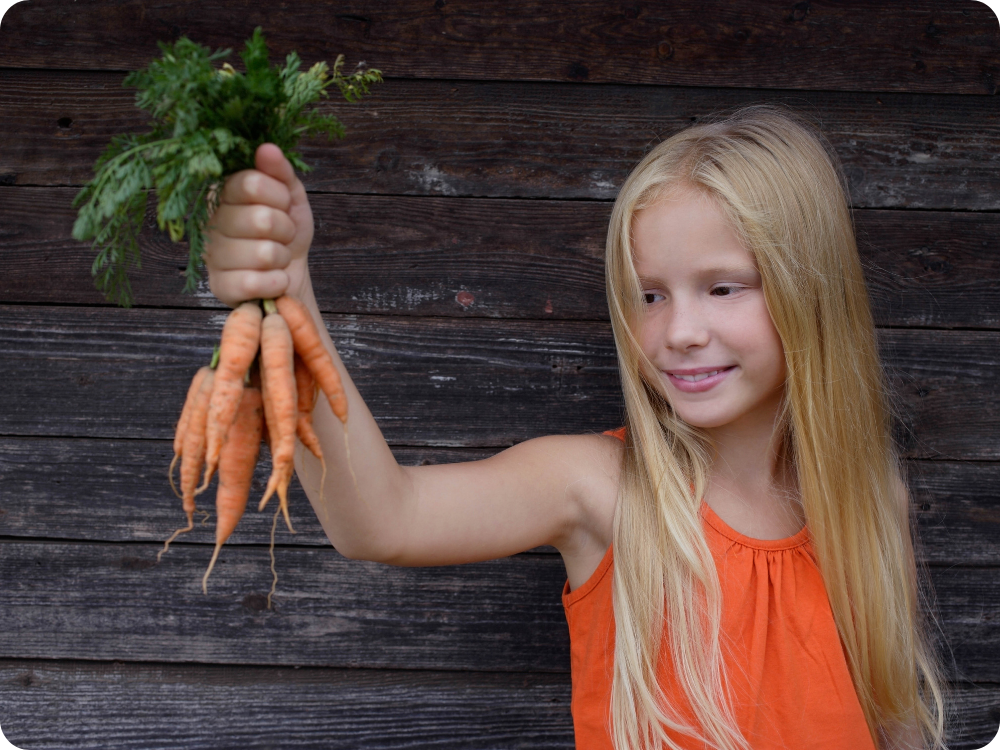 Meisje met worteltjes in haar hand